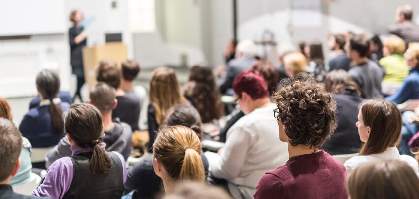 Eine Frau hält einen Vortrag in einem Hörsaal einer Universität.